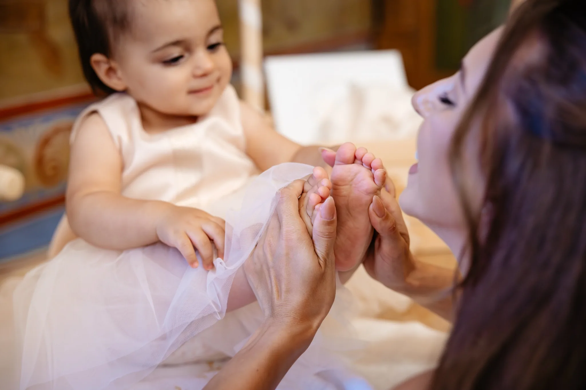 Майка целува бебе по време на кръщене