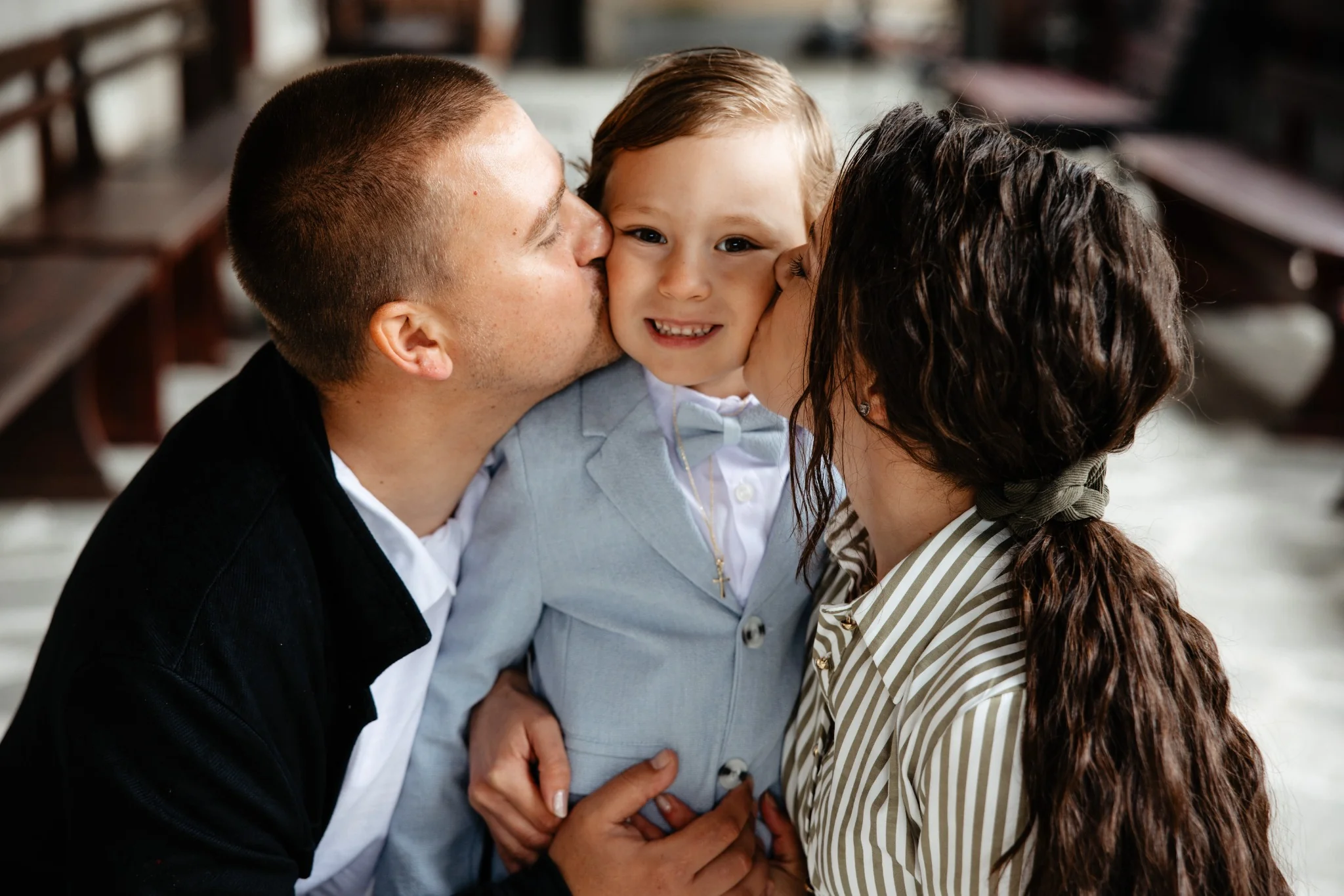 Семейна фотосесия – родители целуват сина си (интериор)