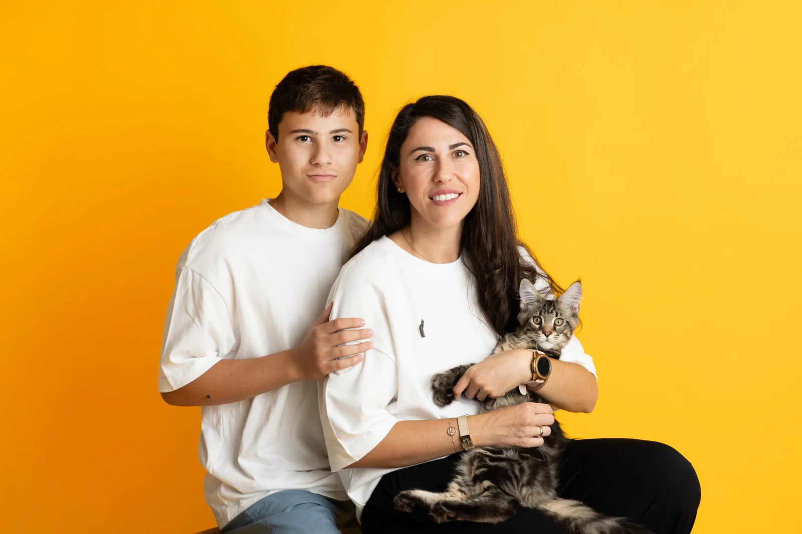 Семеен студиен портрет на майка и син с котенце на жълт фон