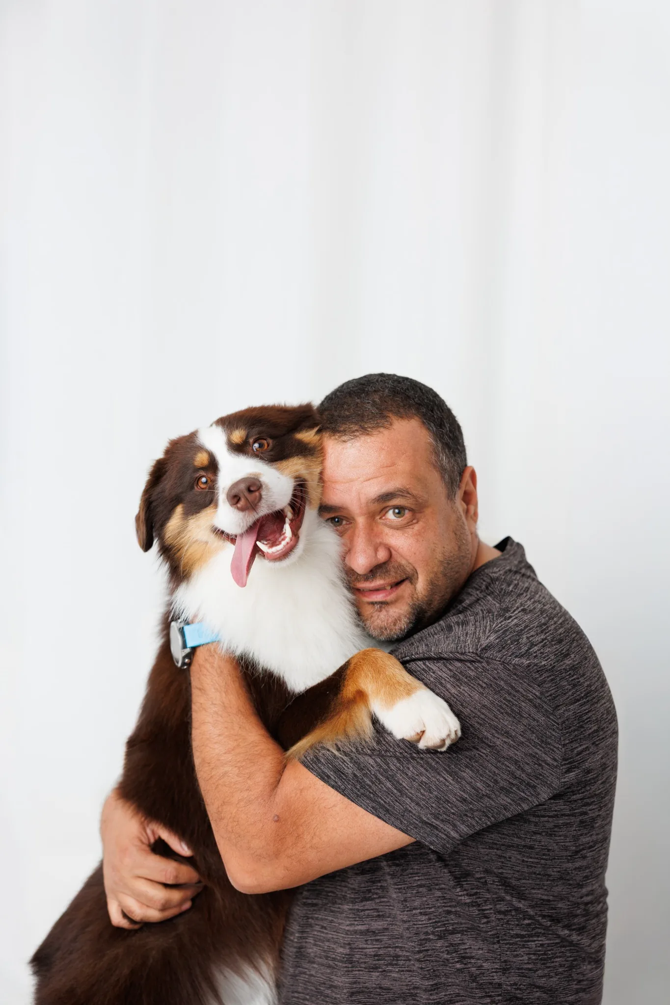 Студиен портрет на мъж, прегръщащ куче на бял фон