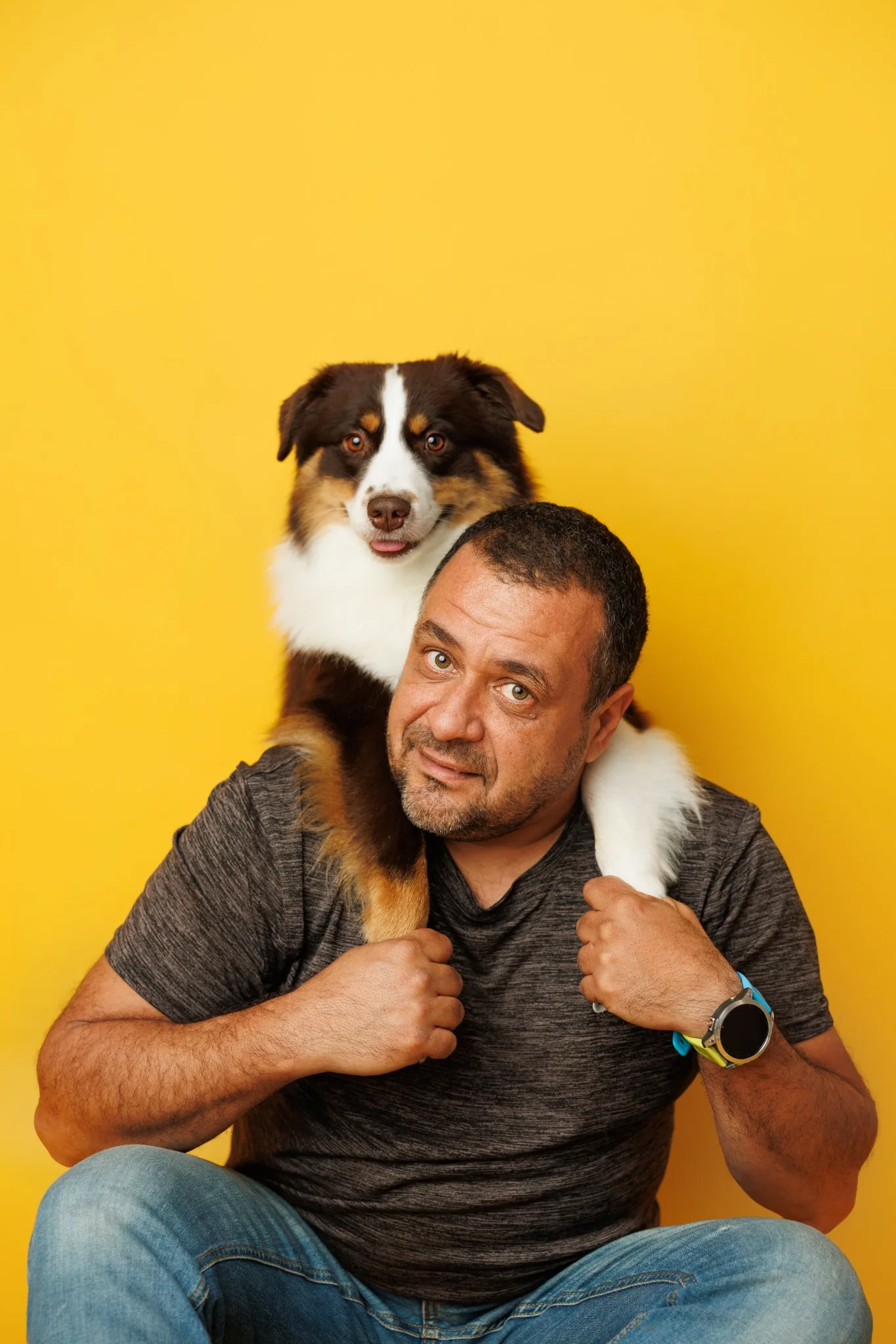 Студиен портрет на мъж с куче на жълт фон